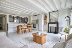 Relax in this spacious living area with a central dining table, comfortable sofa, and cozy fireplace.