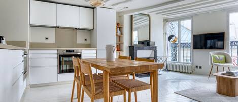 Una cocina moderna con armarios blancos, una mesa de comedor de madera y sillas de mimbre.