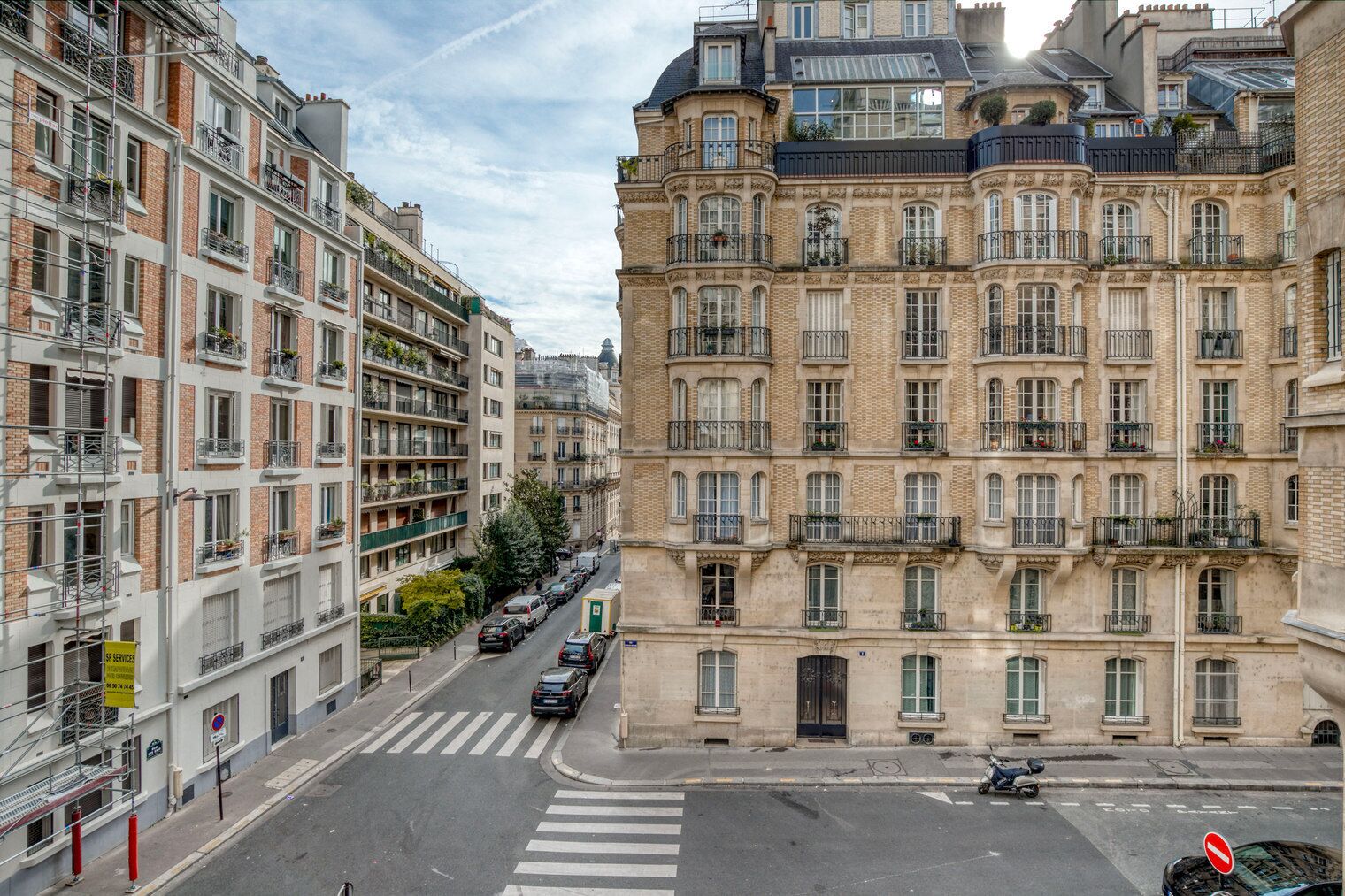 Vista de una calle con una hilera de edificios de varios pisos, algunos con balcones y algunos con señalización visible.