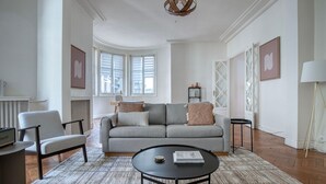 A modern living room with a grey sofa, a round coffee table, and a white armchair. - Blueground | Trocadéro, nr shops & Eiffel Tower (Paris)