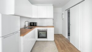 A modern kitchen with white cabinetry, a built-in microwave, a sink, and a wooden countertop. - Blueground | Miromesnil, nr offices & Monceau Park (Paris)