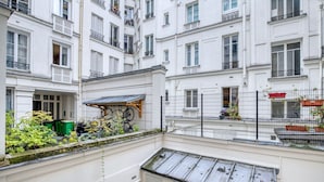 Ein mehrgeschossiges Wohnhaus mit Balkonen, einer überdachten Außenbereich-Sitzgelegenheit und einem umzäunten Innenhof.