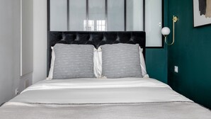 Ein Schlafzimmer mit Bett, einer Kopfteil, einer Wandleuchte und einem gerahmten Kunstwerk.