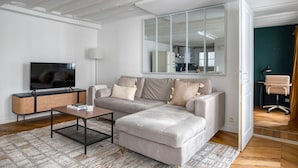 Ein modernes Wohnzimmer mit einem Ecksofa, einem Flachbildfernseher, einem Couchtisch und einem großen Spiegel.