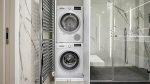 A modern laundry room with two Bosch washing machines, a glass shower enclosure, and a marble-tiled wall. - Blueground | Mairie du XVI, balcony, nr dining (Paris)