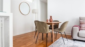 Un salon moderne avec une table ronde en bois, deux chaises, un canapé et une lampe.