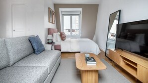 Een moderne slaapkamer met een bed, een televisie, een bank en een nachtkastje.