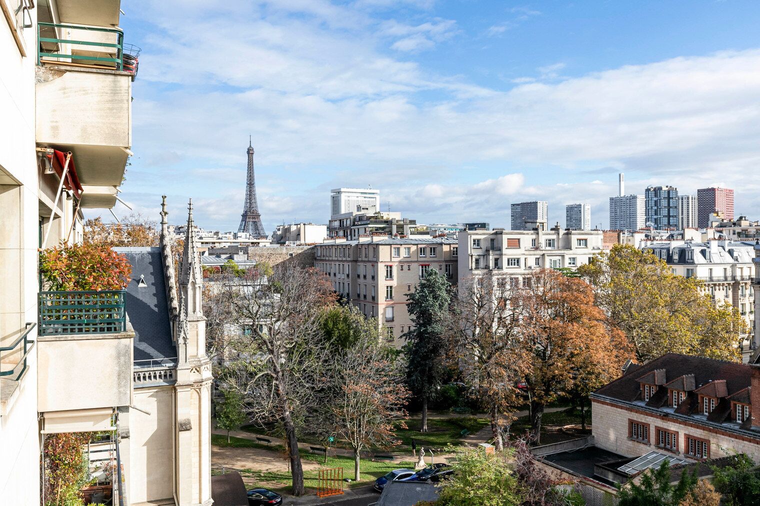 A view of Paris with the Eiffel Tower in the background, surrounded by residential buildings and trees.