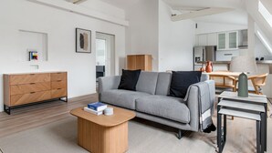 Un salon moderne avec un canapé gris, un buffet en bois et une petite table basse.