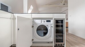 Une petite buanderie équipée d’un lave-linge et d’un sèche-linge à chargement frontal, d’un four à micro-ondes et d’un four encastré.