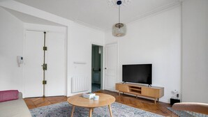 A modern living room with a flat-screen TV, wooden furniture, and a patterned rug. - Blueground | Pigalle, nr shopping & festive area (Paris)