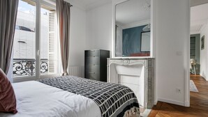A bedroom with a bed, dresser, and a large mirror. - Blueground | Pigalle, nr shopping & festive area (Paris)