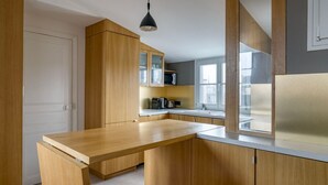 A modern kitchen with wooden cabinets, a countertop, a sink, and a window. - Blueground | Sorbonne, balcony, a/c & great view (Paris)