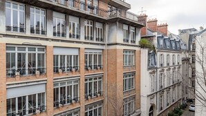 Un immeuble à plusieurs étages, doté de grandes fenêtres, de balcons et d’une façade en briques.
