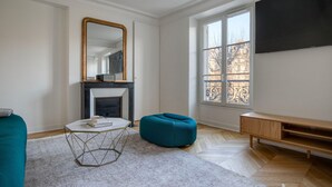 A modern living room with a fireplace, a large window, and a flat-screen TV. - Blueground | Invalides, furnished, nr eiffel tower (Paris)