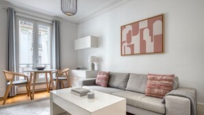 A modern living room with a sofa, coffee table, and a dining area with chairs. - Blueground | Bastille, nr shopping & dining (Paris)