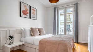 A neatly arranged bedroom with a bed, bedside table, and a view of the outside balcony. - Blueground | Bastille, nr shopping & dining (Paris)