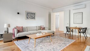 Una sala moderna con un sofá, una mesa de centro y un comedor con sillas.