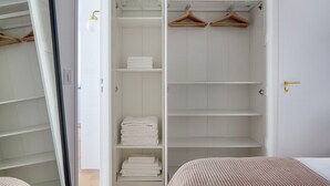 A walk-in closet with multiple shelves, hangers, and a door with a golden handle. - Blueground | Passy, walk to park & foodie area (Paris)