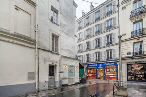 A narrow street with buildings on either side, including a bookstore and a chocolate shop. - Blueground | Passy, walk to park & foodie area (Paris)
