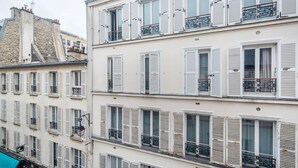 A multi-story building with white facades and shutters, balconies with wrought iron railings, and a visible street sign indicating the address. - Blueground | Passy, walk to park & foodie area (Paris)