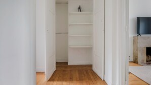 A hallway with a wooden floor leading to a closet with white shelving.