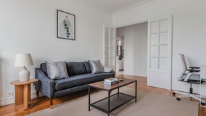 A modern living room with a grey sofa, a coffee table, a lamp, and a framed artwork on the wall.