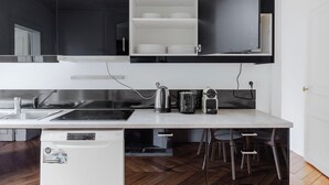 A modern kitchen with a white countertop, stainless steel appliances, and a built-in shelf above the sink. - Blueground | Jardin du Luxembourg, walk to gardens (Paris)