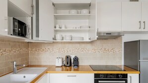 Eine moderne Küche mit weißen Schränken, einer Mikrowelle, einem Toaster, einem Wasserkocher, einem Herd und einem Geschirrspüler.
