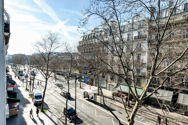 A street view with buildings, trees, and a clear sky.