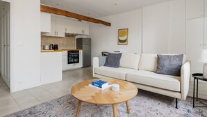 Ein modernes Wohnzimmer mit Sofa, Couchtisch und einer Küche im Hintergrund.