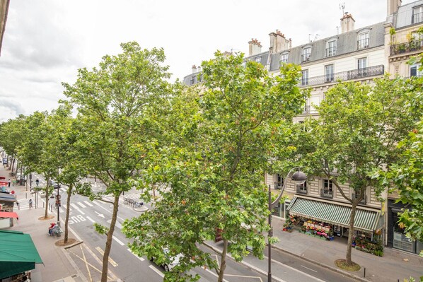 A street lined with trees and buildings, including a flower shop.