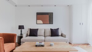A modern living room with a sofa, a coffee table, a lamp, and a wardrobe. - Blueground | Jardin du Luxembourg, walk to gardens (Paris)