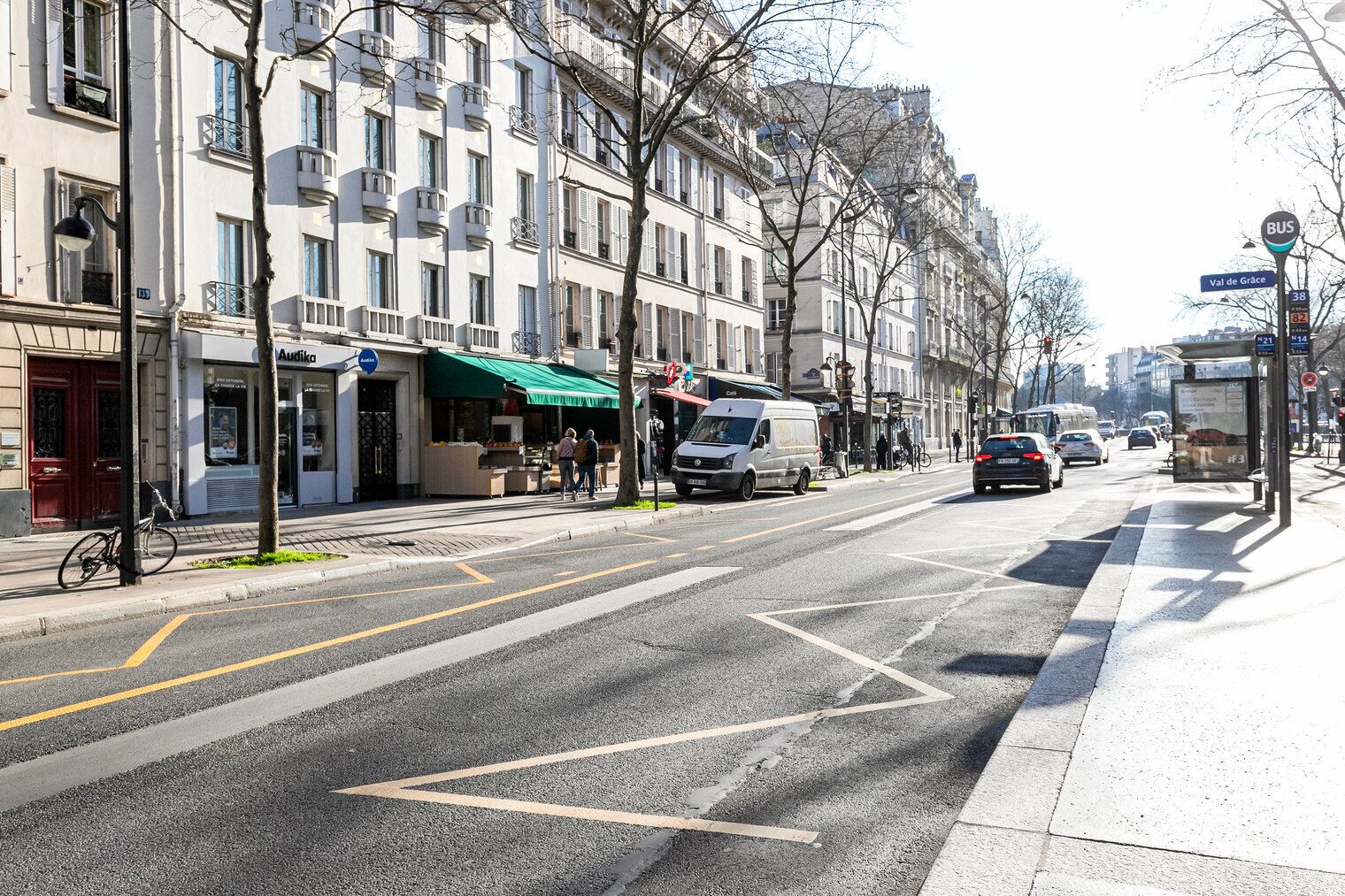 Una strada con edifici, una fermata dell'autobus e un furgone parcheggiato a lato.