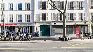 Une rue bordée de motos garées, un concessionnaire Honda et un immeuble avec une porte verte.