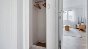Ein Flur, der zu einem Badezimmer mit Holzboden, einem weißen Waschbecken und einem Fernseher auf einem Holztisch führt.