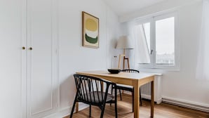 Ein Essbereich mit Holztisch und schwarzen Stühlen, einer Lampe und einem Fenster mit Vorhängen.