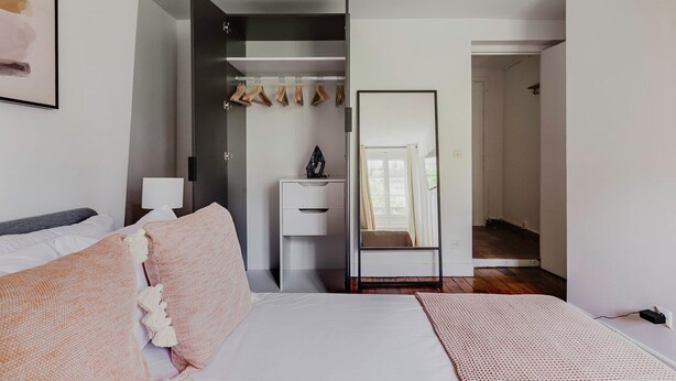 A bedroom with a bed, bedside table, wardrobe, and a mirror. - Blueground | Jardin du Luxembourg, near gardens (Paris)