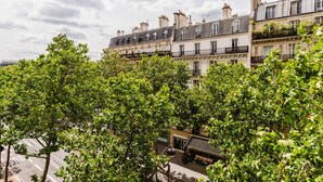 A row of multi-story buildings with balconies, surrounded by lush green trees. - Blueground | Jardin du Luxembourg, near gardens (Paris)