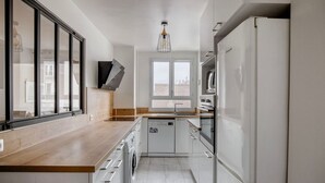 Una cocina moderna con encimera de madera, armarios blancos, horno integrado y ventana que proporciona luz natural.