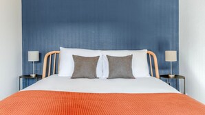A bed with two pillows, a wooden headboard, and two bedside lamps. - Blueground | Quartier Latin, near gardens (Paris)