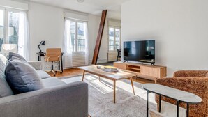 A modern living room with a sofa, coffee table, TV, and a chair. - Blueground | Quartier Latin, near gardens (Paris)