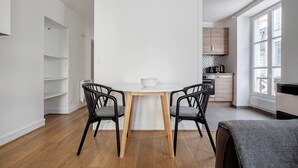 Una cocina moderna con armarios blancos, una mesa de comedor de madera y dos sillas negras.