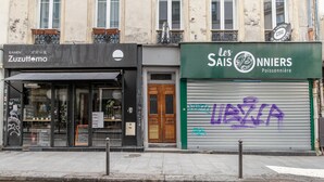 Vista de la calle con tiendas, incluyendo un restaurante llamado "Les Saisons" y una tienda llamada "Zuzutemo".
