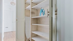 A closet with open doors, revealing empty shelves and a hanging garment.