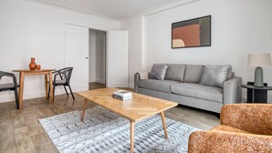 Una sala de estar moderna con una mesa de centro de madera, sofá gris y una mesita auxiliar con una lámpara.