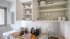 Una cocina compacta con horno integrado, cafetera, tostadora y pileta.