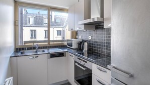 Une cuisine compacte dotée d ’une fenêtre, d’un four à micro-ondes, d’une bouilloire et d’un lave-vaisselle.
