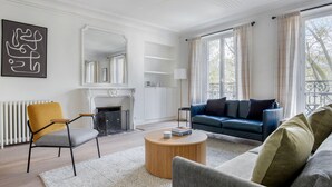 A modern living room with a fireplace, a sofa, a coffee table, and a chair. - Blueground | Pigalle, nr restaurants & boutiques (Paris)