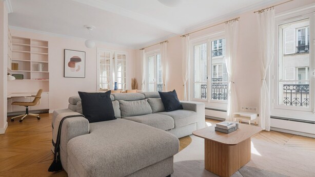 A modern living room with a grey sectional sofa, a wooden coffee table, and a desk with a chair. - Blueground | Pigalle, nr dining & shopping (Paris)